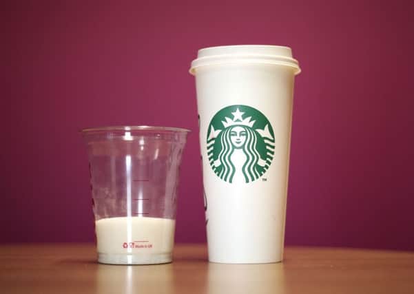 A cup of Starbucks' venti Grape with Chai, Orange and Cinnamon Hot Mulled Fruit which had a total of 25 teaspoons of sugar per serving next to with a cup containing 25 teaspoons of sugar