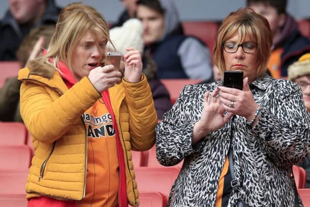 Hull City fans on their mobile phones in the stands before the Emirates FA Cup, fifth round match.