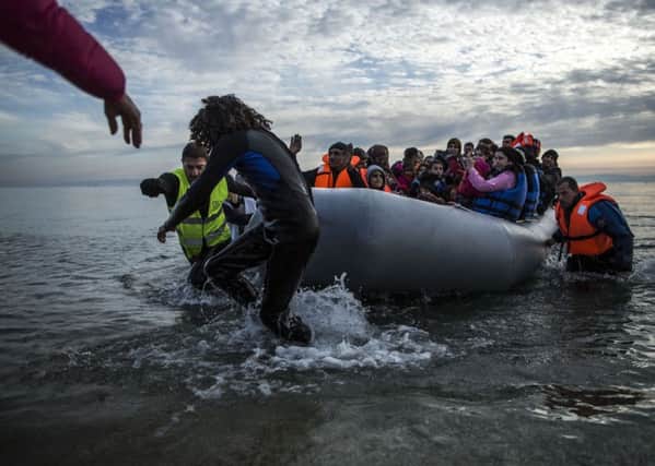 Refugees and migrants are helped by volunteers on their arrival aboard a dinghy at Mytilene on the northeastern Greek island of Lesbos, Tuesday, Feb. 23, 2016. Nearly 100,000 migrants and refugees have travelled to Greek islands from nearby Turkey so far this year.