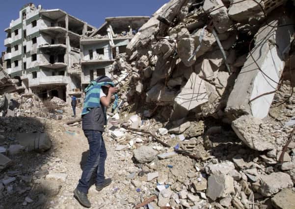 A Syrian covers his face as he walks with a friend between destroyed buildings in the old city of Homs, Syria.
