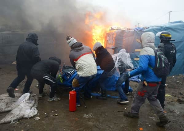 Migrants and activists clear a tent away from a fire in the Calais migrant camp, known as the Jungle, as demolition of the camp resumes in Calais, France.