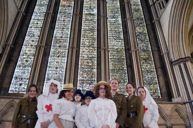 Mount students, dressed in World War One contemporary style, stand before the Five Sisters' Window of York Minster.