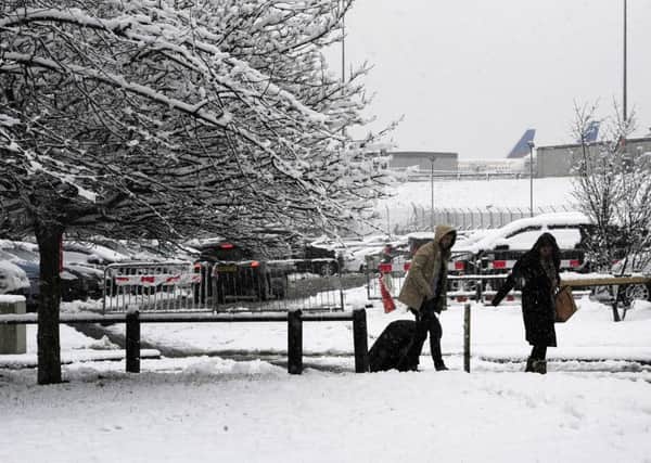 Passengers make their way through the snow to Leeds Bradford Airport which was forced to close while crews worked to clear the runway, as parts of the UK woke up to almost four inches of snow on Friday morning.