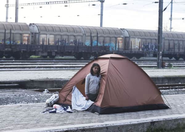 A girl looks from her tent set up near a train station of Idomeni as she and her family are waiting to be allowed to cross the border into Macedonia.