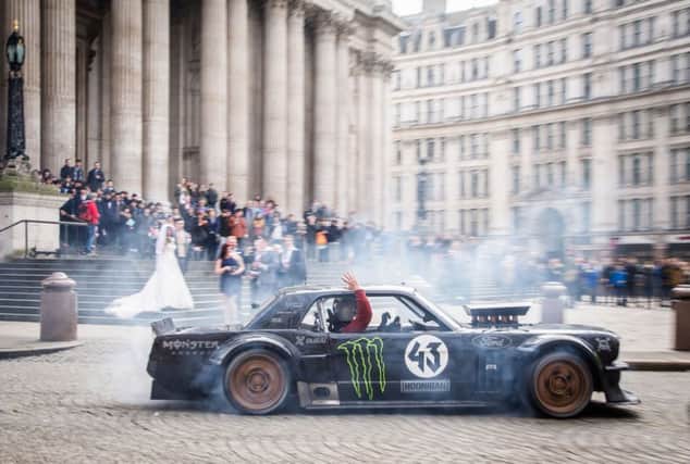Host Matt LeBlanc waving to a bride and groom and their wedding guests at St Paul's Cathedral in London as he went past with rally driver Ken Block.