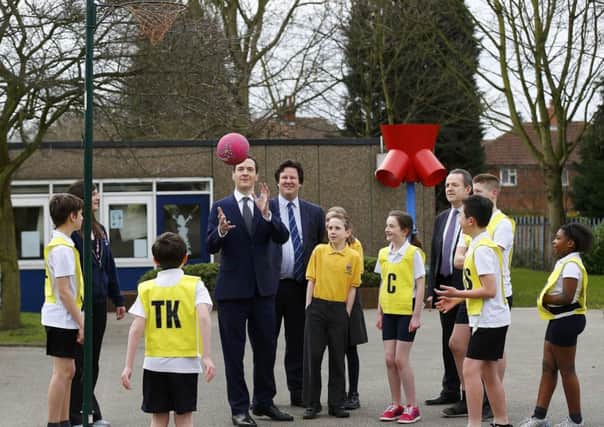 Chancellor George Osborne watches pupils during a netball lesson  at St Benedict's Catholic Primary School in Garforth, Leeds, on the day after he delivered his Budget Statement.