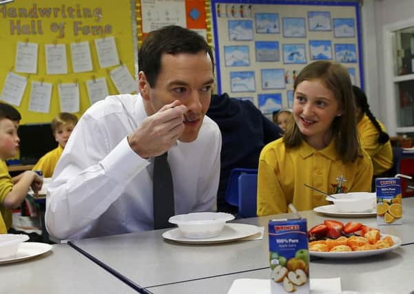 Chancellor of the Exchequer George Osborne eats with pupils during breakfast club at St Benedict's Catholic Primary School in Garforth on the day after he delivered his Budget statement.
