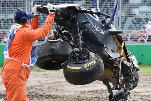 A track official assists the removal of McLaren driver Fernando Alonso.