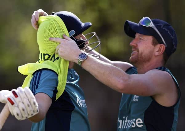 IN A TANGLE: England coaching staff member Paul Collingwood, right, extricates Joe Root from his bib in the nets. Picture: AP/Saurabh Das.