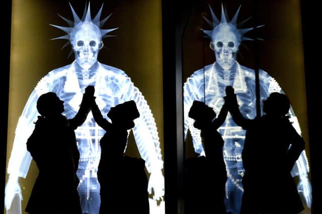 Silhouettes of Lee Clark dressed as a Georgian 'Macaroni' with Eve Haynes dressed in a Victorian Bustle dress against some astwork 'X rays' by Nick Veasey at the new 'Shaping The Body' exhibition at York's Castle Museum .