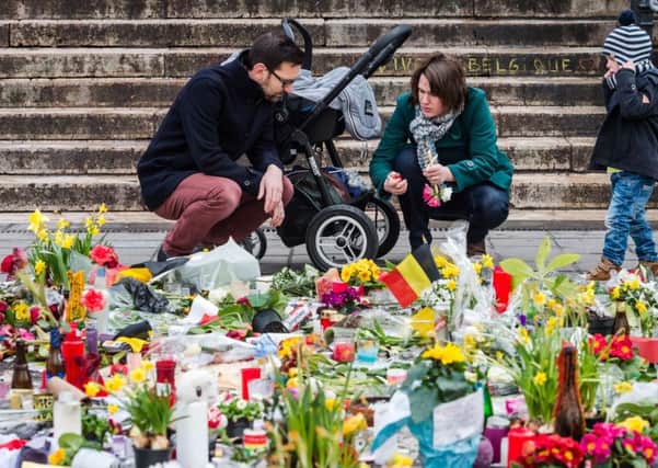 A family lights a candle at floral tributes at a memorial site at the Place de la Bourse in Brussels, Sunday.