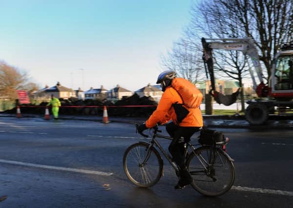 A cyclist rides past workmen tasked with building a cycle superhighway from Leeds to Bradford.