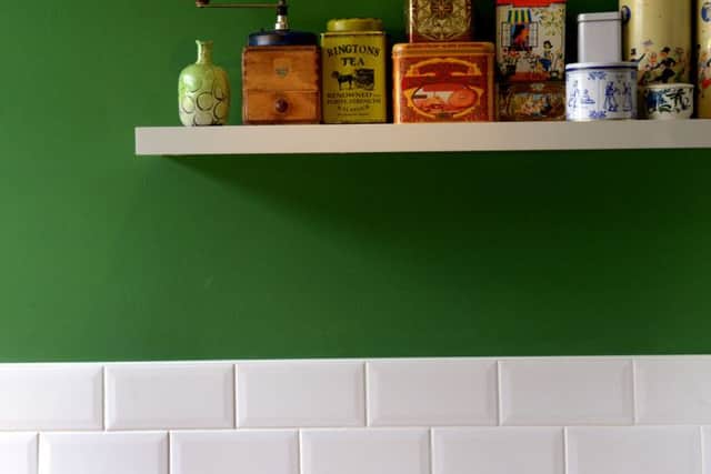 The kitchen has a green feature wall and the shelf holds the couple's collection of old tins