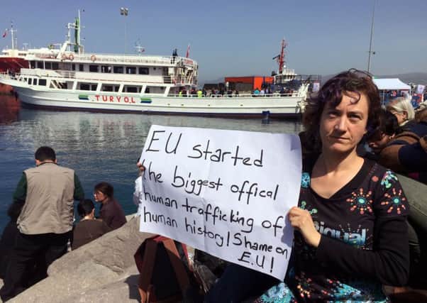 A woman holds a placard as a vessel transporting migrants from Greek island of Lesbos arrives to dock in Dikili port, Turkey, on Monday.