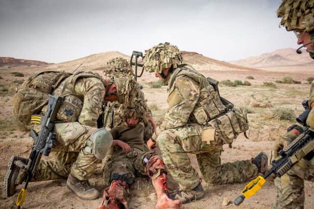 British soldiers treat an 'injured' solider as they take part in a training exercise repelling an opposition force on an exercise in the Jordanian desert. Picture: SWNS
