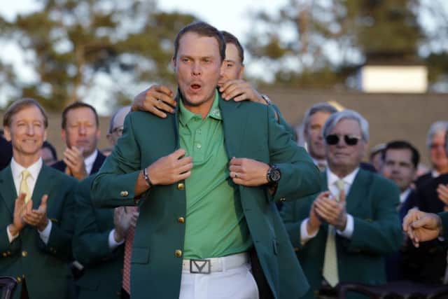 Defending champion Jordan Spieth, left, helps 2016 Masters champion Danny Willett, of England, put on his green jacket following the final round of the Masters golf tournament Sunday, April 10, 2016, in Augusta. (AP Photo/Jae C. Hong)