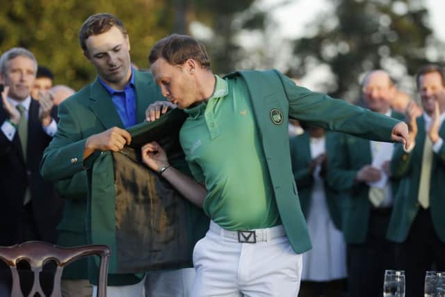 Defending champion Jordan Spieth, left, helps 2016 Masters champion Danny Willett, of England, put on his green jacket following the final round of the Masters golf tournament.  (AP Photo/Chris Carlson)