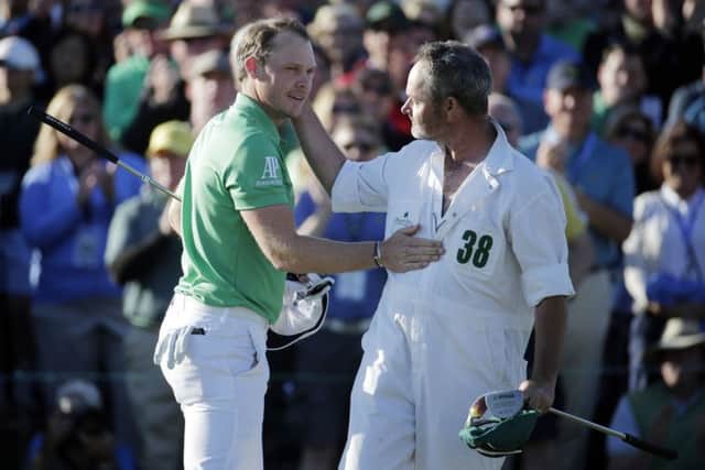 Danny Willett, of England, is congratulated by Lee Westwood's caddie Billy Foster on the 18th hole after finishing the final round of the Masters golf tournament. (AP Photo/Charlie Riedel)