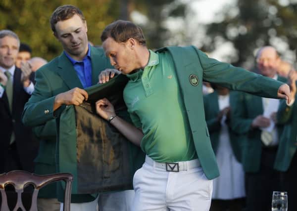 Defending champion Jordan Spieth, left, helps 2016 Masters champion Danny Willett, of England, put on his green jacket following the final round of the Master.  (AP Photo/Chris Carlson)
