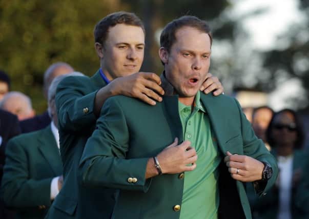 Danny Willett's reaction seems to indicate that he thinks the Masters green jacket fits him a treat as defending champion Jordan Spieth gives a helping hand(Picture: Chris Carlson/AP).