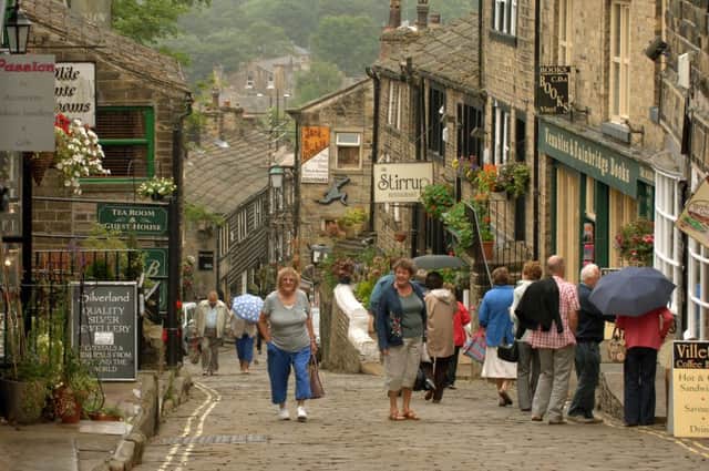 Visitors to Haworth walk up and down the  famous cobbled main street.