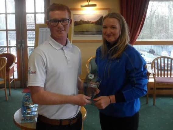 Under-19 boys' champion Nathan Fell hands Under-19 girls' champion Laura Morrison her trophy at Hickleton GC.
