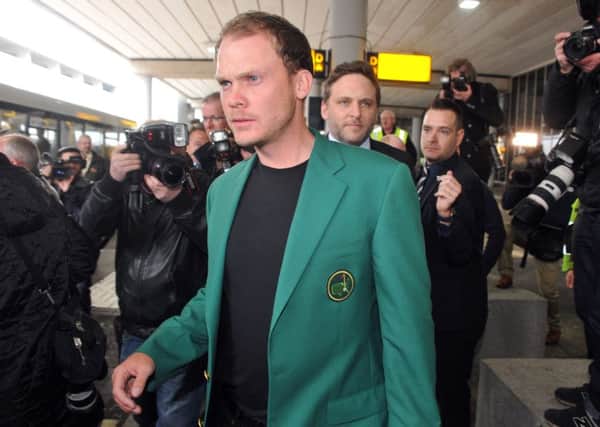 Masters champion emerges to a tunnel of photographers at Manchester Airport yesterday. Picture: Tony Johnson