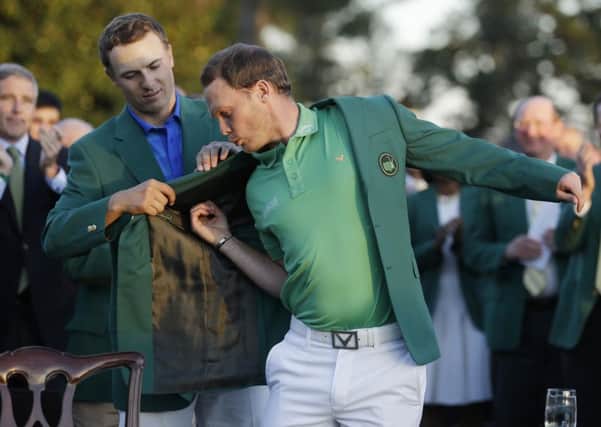 Defending champion Jordan Spieth, left, helps 2016 Masters champion Danny Willett, of England, put on his green jacket following the final round of the Masters (AP Photo/Chris Carlson)