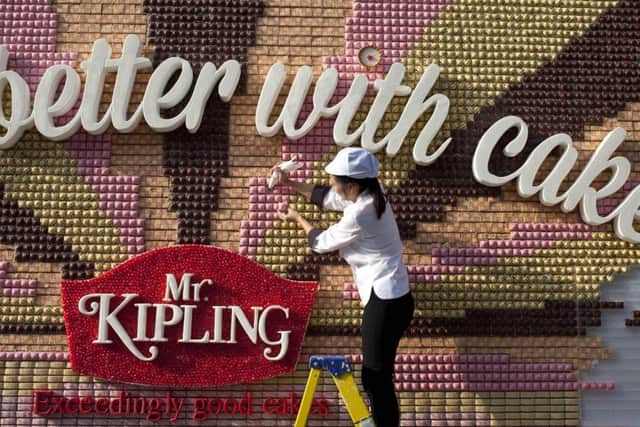 Food artist Michelle Wibowo puts the finishing touches to an edible poster made from over 13,000 Mr Kipling cakes. David Parry/PA
