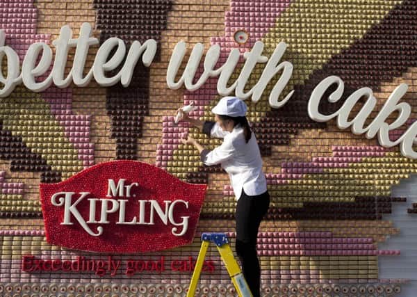 Food artist Michelle Wibowo puts the finishing touches to an edible poster made from over 13,000 Mr Kipling cakes. David Parry/PA