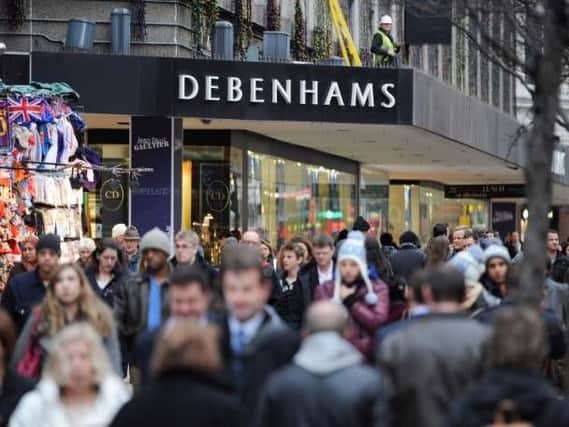 People walk past Debenhams department store on Oxford Street,