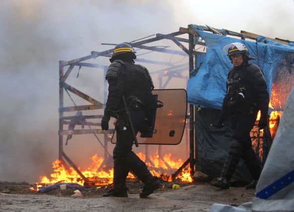 A makeshift shelter burns while French riot police look on in the Calais migrant camp, known as the Jungle, as demolition of the camp resumes in Calais, France. PRESS ASSOCIATION Photo. Picture date: Tuesday March 1, 2016. French officers fired tear gas as some makeshift shelters were set on fire as tensions over the mass eviction of the camp's southern section escalated overnight. See PA story POLITICS Calais. Photo credit should read: Gareth Fuller/PA Wire