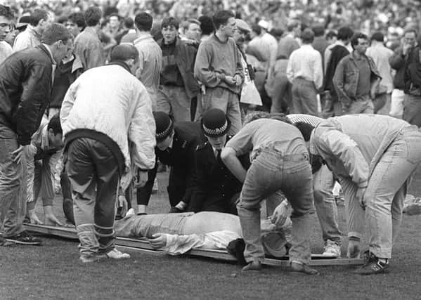 Fans and a police officer come to the aid of a victim of the Hillsborough tragedy.