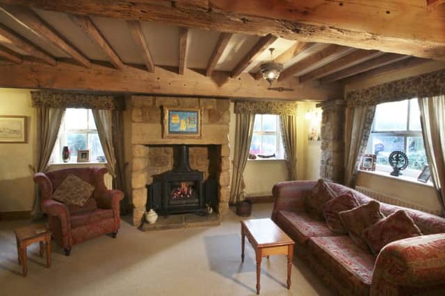 The sitting room is in a recently extended part of the property that blends with the rest of the cottage thanks to reclaimed beams and a stone fireplace