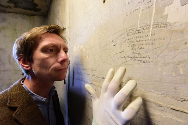 English Heritage Senior Curator Kevin Booth examines graffiti left by a conscientious objector during the First World War at Richmond Castle. Photograph: Anthony Chappel-Ross for English Heritage.