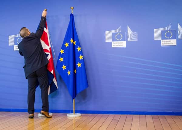 An EU official hangs the Union Jack next to the European Union flag at the VIP entrance at the European Commission headquarters.