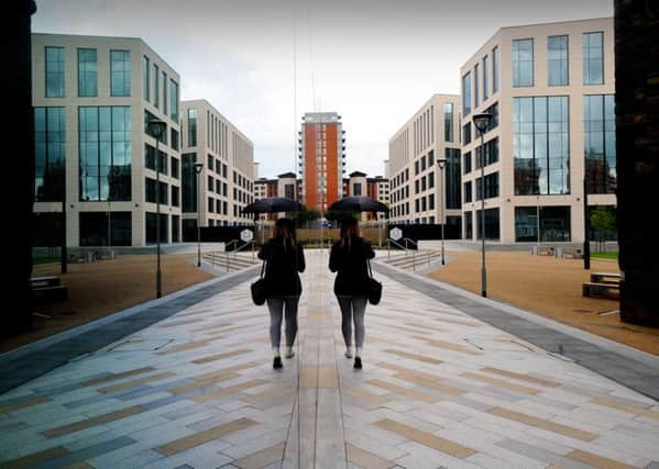 Mirror image of a woman as she walks through Wellington Place in Leeds. The office park is growing the number of buildings on its site....Picture by Simon Hulme