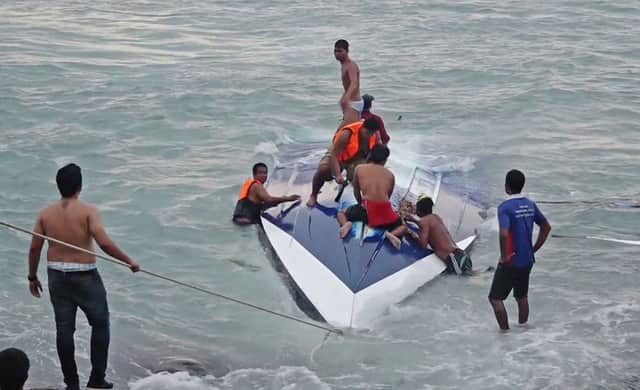 People search for a woman feared trapped under an upturned boat.