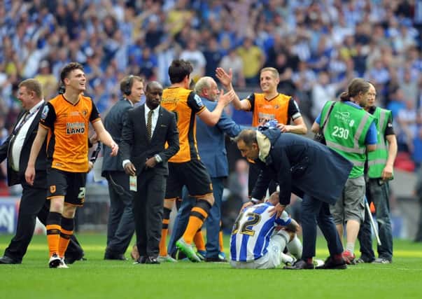 Wednesday manager Carlos Carvalhal consoles  Jack Hunt as Hull celebrate promotion.  Picture Tony Johnson .