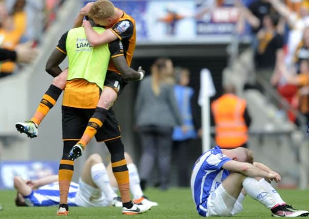 TWO SIDES: Hull City players celebrate their return to the Premier League, while Sheffield Wednesday can only contemplate what might have been. Picture: Steve Ellis.