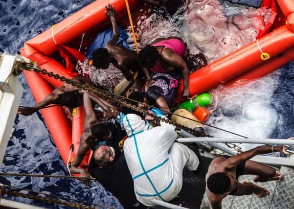 In this photo taken in the Mediterranean Sea, off the Libyan coast, Friday, May 27, 2016 rescuers help migrants to board the Italian Navy ship Vega, after the boat they were aboard sunk.