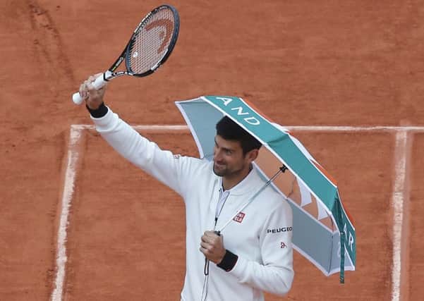 Serbia's Novak Djokovic walks onto center court with an umbrella before resuming his fourth round match of the French Open.