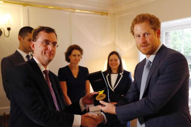 Prince Harry (right) hands over an Invictus Games gold medal won by Elizabeth Marks to consultant intensivist Dr Alain Vuylsteke, originally from Belgium, and the other members of the Papworth Hospital medical team who helped save the servicewoman's life, as they visit Kensington Palace in London.Picture: Matt Dunham/PA Wire