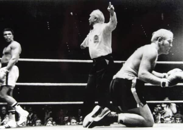 Richard Dunn raises his fists in desperation after being knocked down for the second time in his heavyweight world title fight against Muhammad Ali. Dunn lost the fight in the fifth round after a technical knockout.