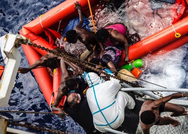 In this photo taken in the Mediterranean Sea, off thRescuers help migrants to board the Italian Navy ship Vega, after the boat they were aboard sunk.