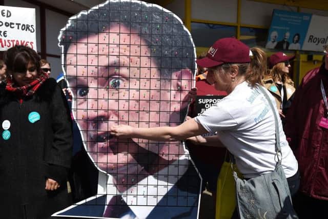 A member of the CWU pins a pin to a cardboard cut out of Health Secretary Jeremy Hunt as members of the union join junior doctors on the picket lines.