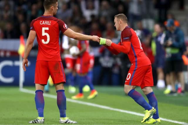 England's Gary Cahill (left) hands the captain's armband to team-mate Wayne Rooney (centre)