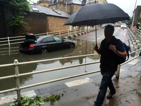 A car stranded on Queenstown Road, Battersea, London, in standing water after heavy overnight rain.