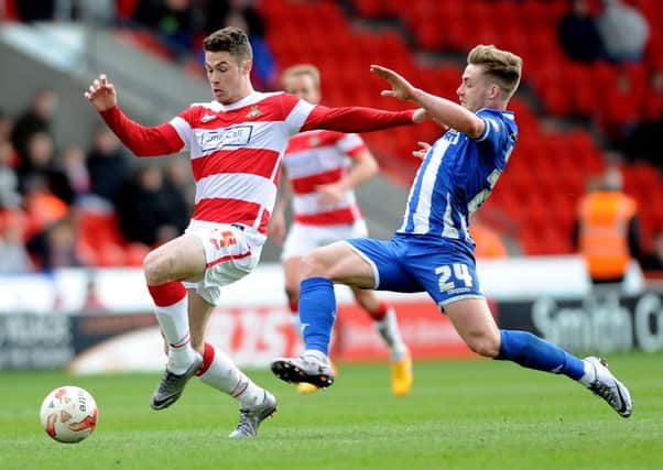 Date:28th March 2016. Picture James Hardisty. Doncaster Rovers V Wigan Athletic. Pictured Doncaster Rovers Tommy Rowe, is challenged for the ball by Wigan Athletic Conor McAleny