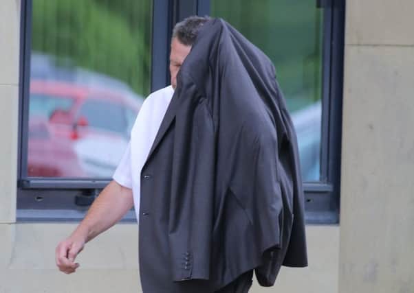 Stuart Moore, 53, hides his face as he arrives at Bradford Crown Court. Picture: Ross Parry Agency